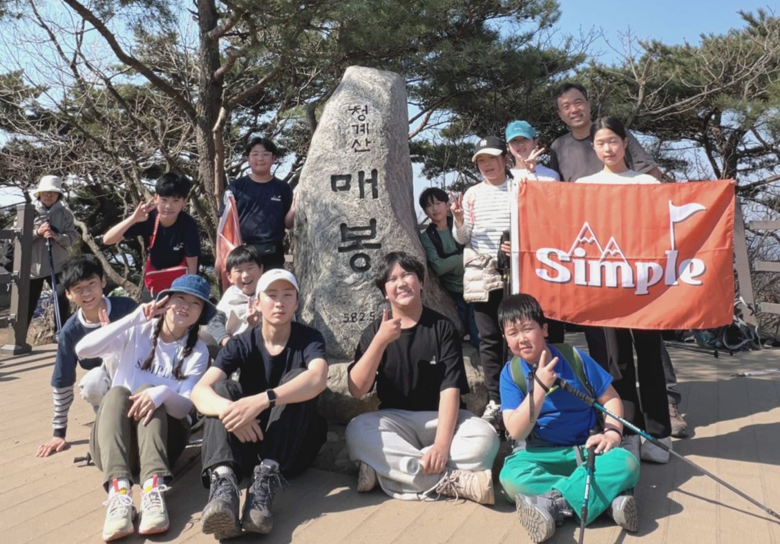 산 정상 표지석 앞에서 심플 깃발을 들고 찍은 단체 사진