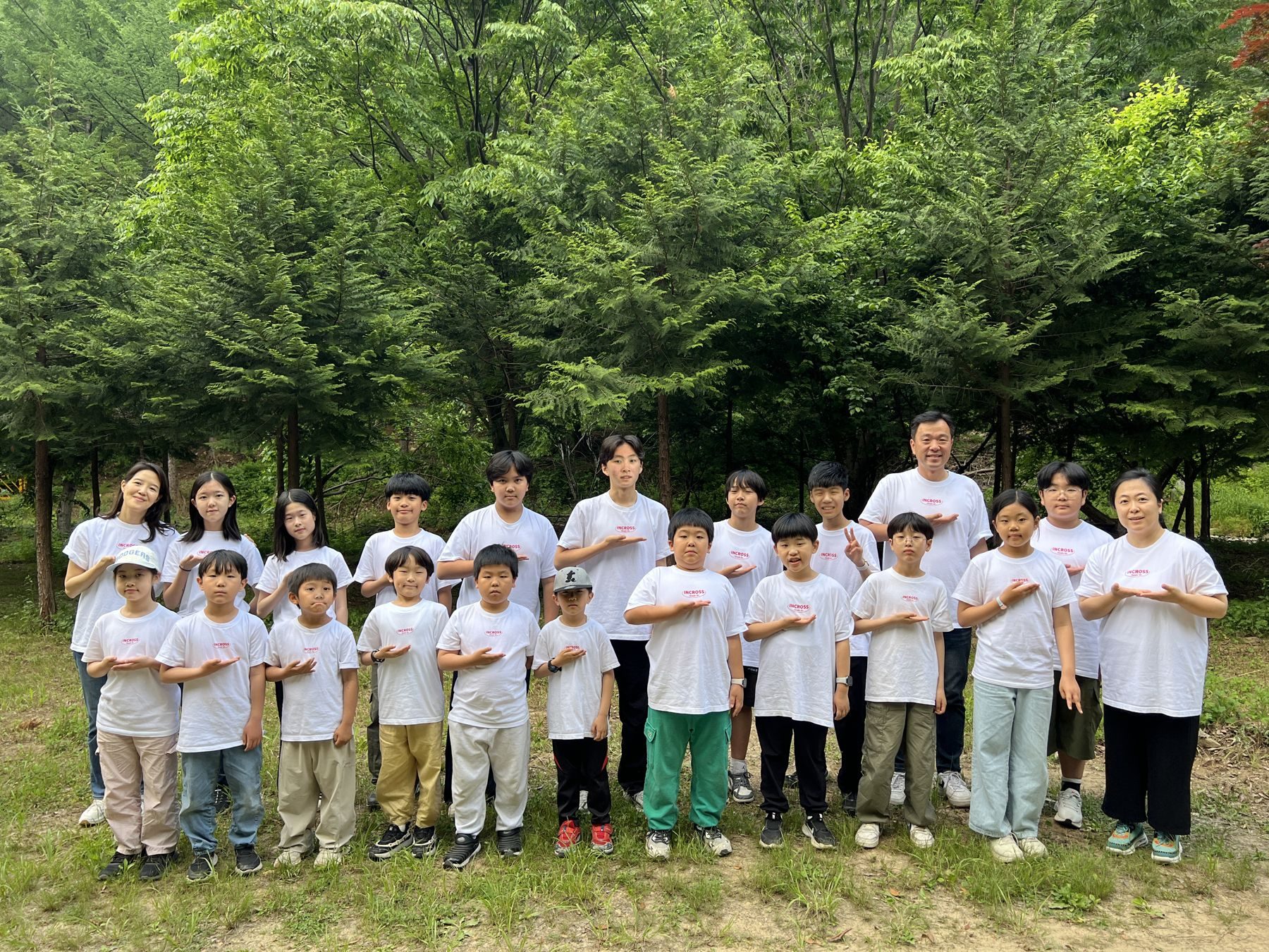 숲 앞에 함께 선 학생과 교사들의 단체 사진