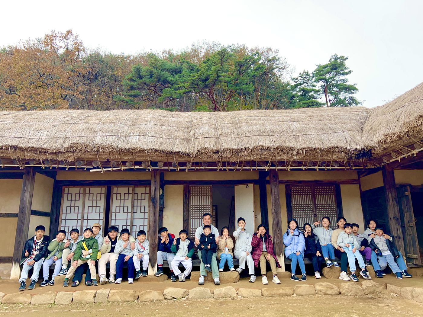 초가 마루에 나란히 앉은 학생과 교사들