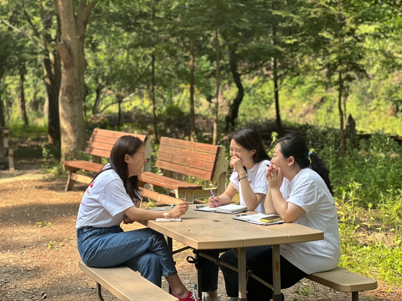 숲속 탁자에 둘러앉아 이야기를 나누는 교사들