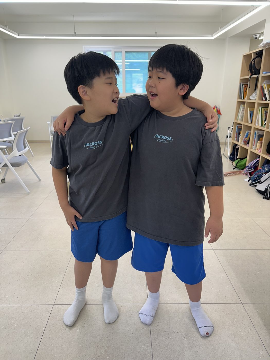 서로 어깨에 팔을 두르고 웃는 두 학생
